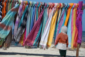Bunte Tücher und Schals am Strand mit Kind